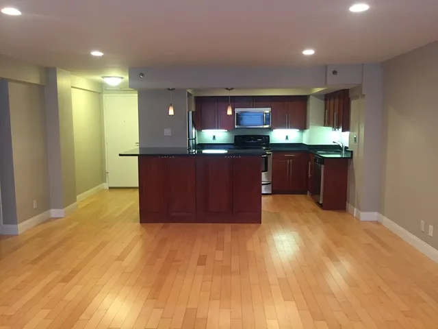 a kitchen with kitchen island a sink wooden floor and a refrigerator