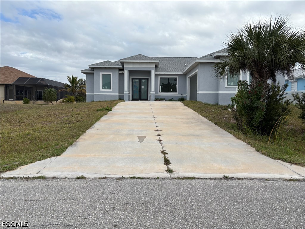 front view of house with a yard and palm trees
