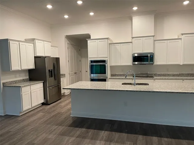 a kitchen with stainless steel appliances granite countertop a refrigerator a stove a microwave and white cabinets