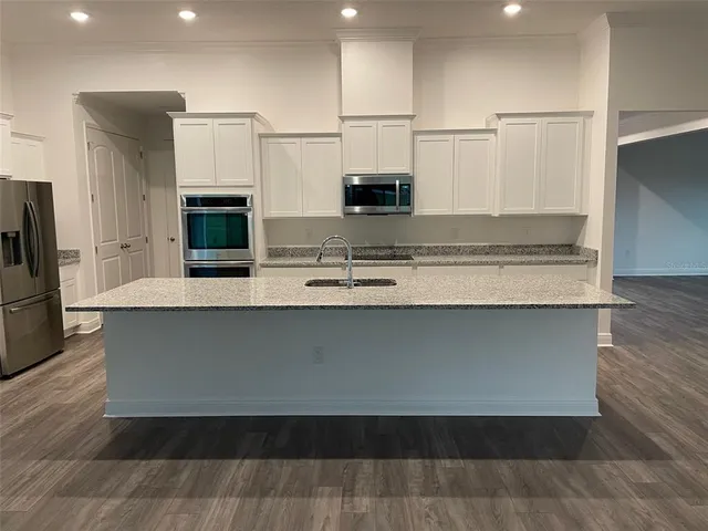 a kitchen with stainless steel appliances granite countertop a refrigerator and a stove top oven