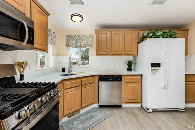 a kitchen with stainless steel appliances a stove a sink and a refrigerator