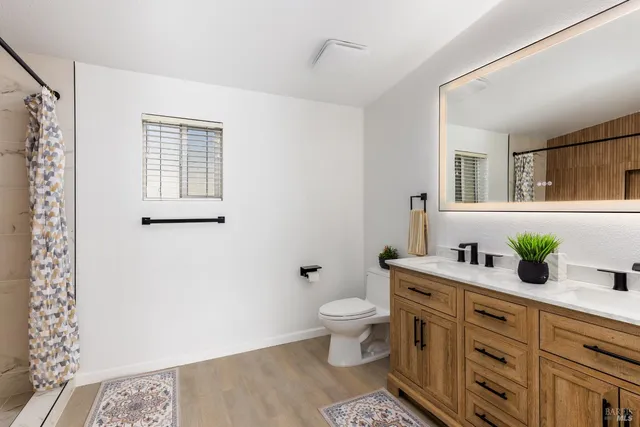 a spacious bathroom with a double vanity sink a mirror and a toilet