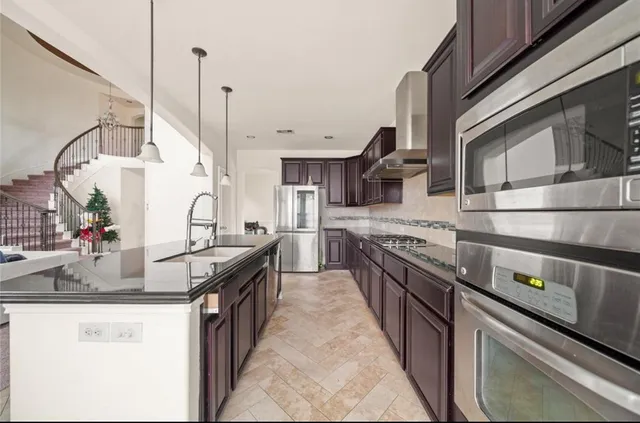 a kitchen with stainless steel appliances granite countertop a sink a stove and a refrigerator