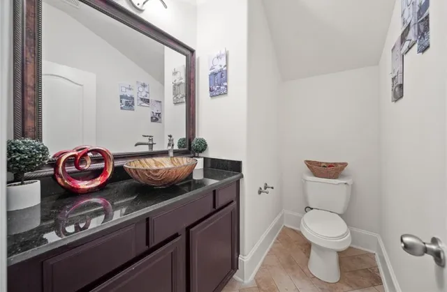 a bathroom with a granite countertop toilet sink and mirror