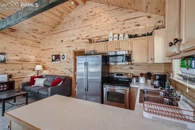 a kitchen with stainless steel appliances kitchen island granite countertop a refrigerator and wooden cabinets