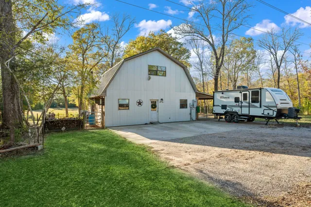 a view of a white house next to a yard and a large tree