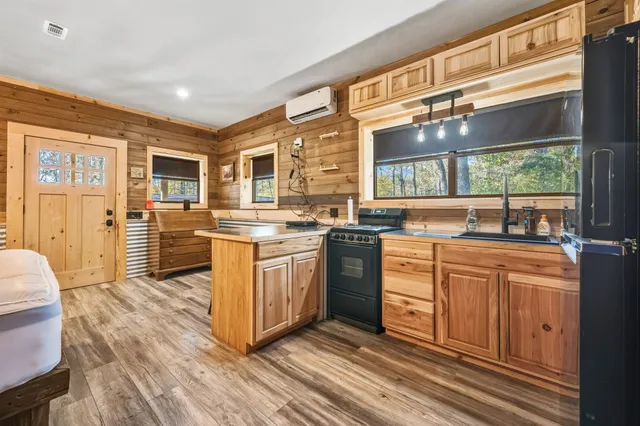 a kitchen with stainless steel appliances granite countertop a stove top oven a sink dishwasher a dining table and chairs with wooden floor