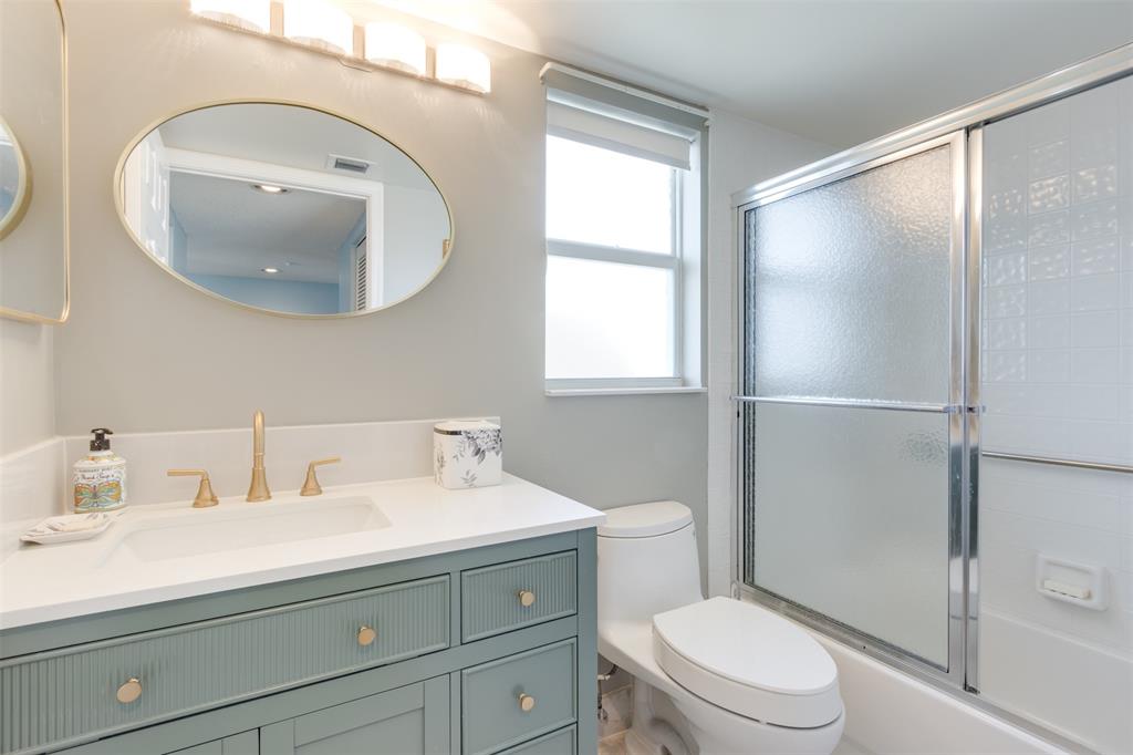 9539 Weldon Circle, Unit F201 Tamarac, FL 33321 - Photo 17 of 33 a bathroom with a sink a mirror a toilet and shower