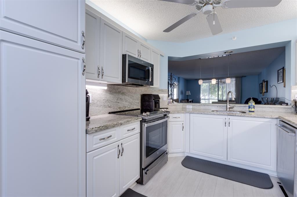 9539 Weldon Circle, Unit F201 Tamarac, FL 33321 - Photo 2 of 33 a kitchen with white cabinets and appliances
