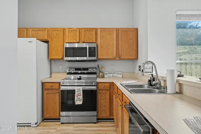 a kitchen with stainless steel appliances granite countertop a sink a stove and a window with wooden floor