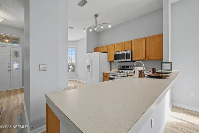 a view of a kitchen island a sink wooden floor and a living room