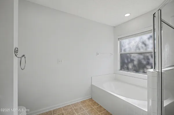 a view of an empty room with window and a ceiling fan