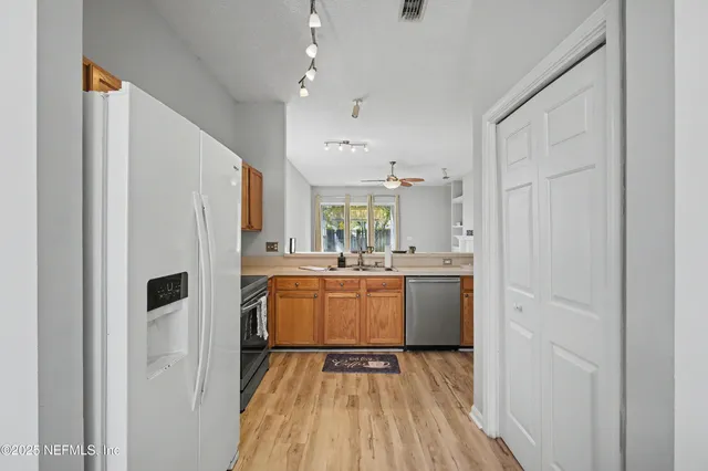 a kitchen with kitchen island wooden floor center island and stainless steel appliances