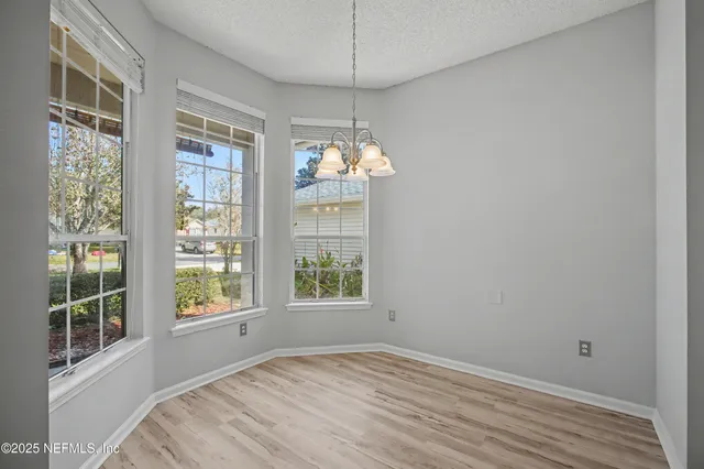 a view of an empty room with windows and chandelier