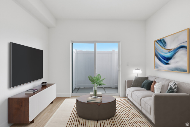 2085 North Main Street, Unit 216 Sunset, UT 84015 - Photo 4 of 12 Living area featuring wood-finish flooring, a contemporary built-in media console, and a sliding glass door leading to an outdoor patio with privacy fencing