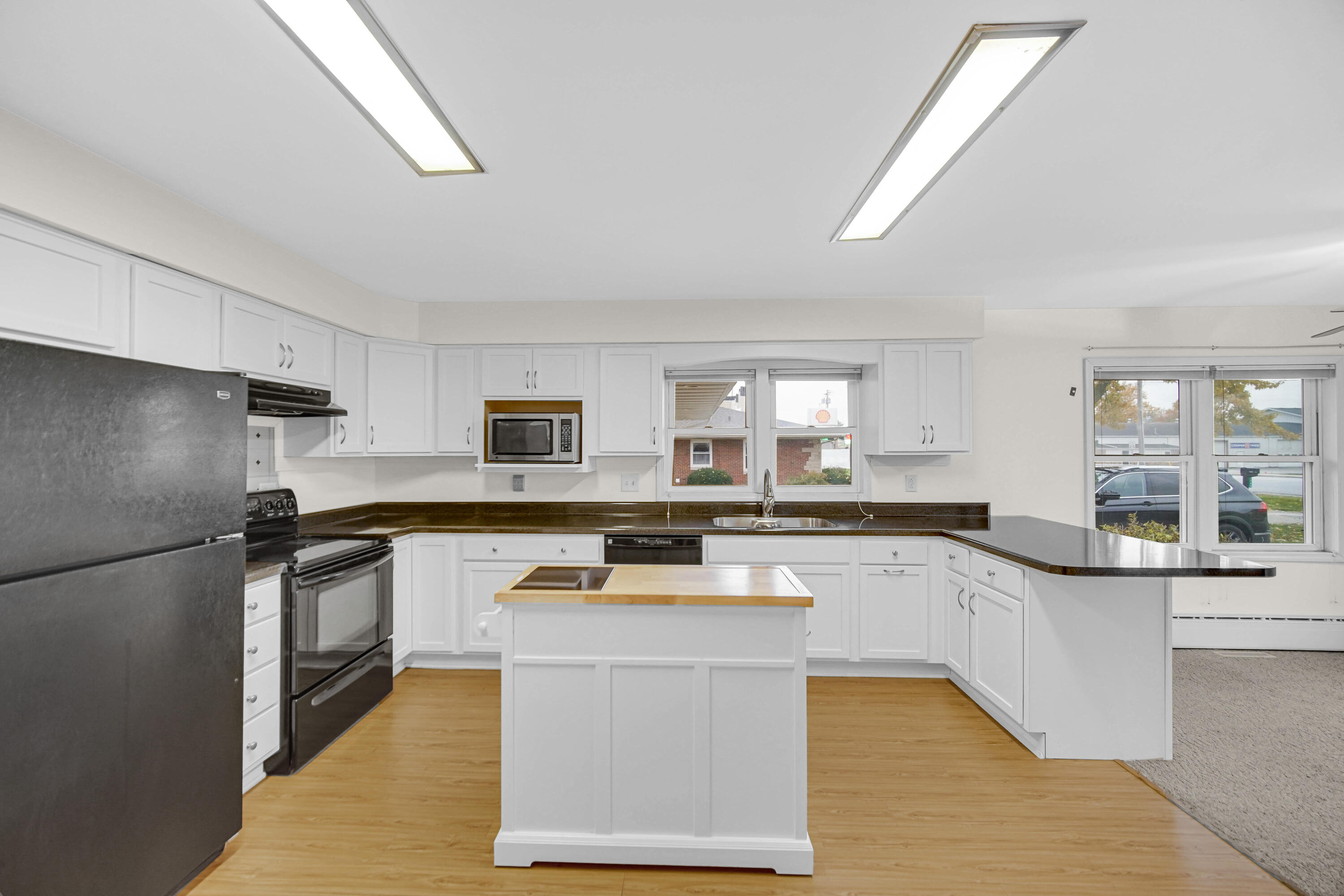 204 North Main Street Kouts, IN 46347 - Photo 9 of 28 a kitchen with stainless steel appliances granite countertop a stove a sink dishwasher a refrigerator and white cabinets with wooden floor