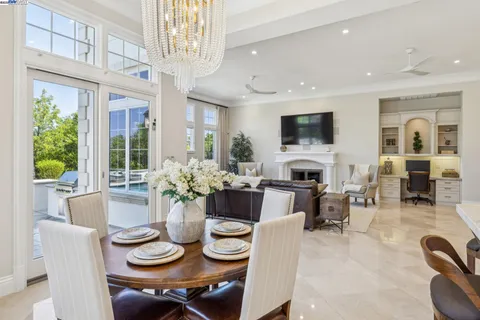 a room with stainless steel appliances kitchen island granite countertop a table chairs in it and wooden floors