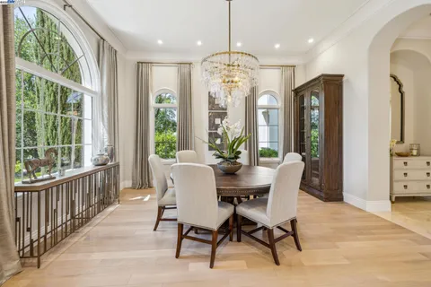 a kitchen with stainless steel appliances a stove a sink dishwasher a dining table and chairs with wooden floor