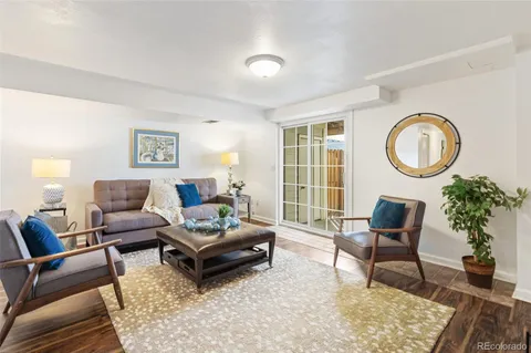a living room with furniture a rug a lamp and a large window