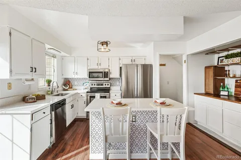 a kitchen with stainless steel appliances kitchen island granite countertop a sink stove and refrigerator