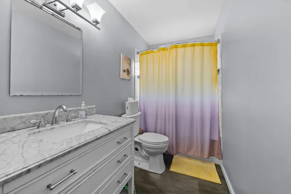 a bathroom with a granite countertop sink toilet and a mirror