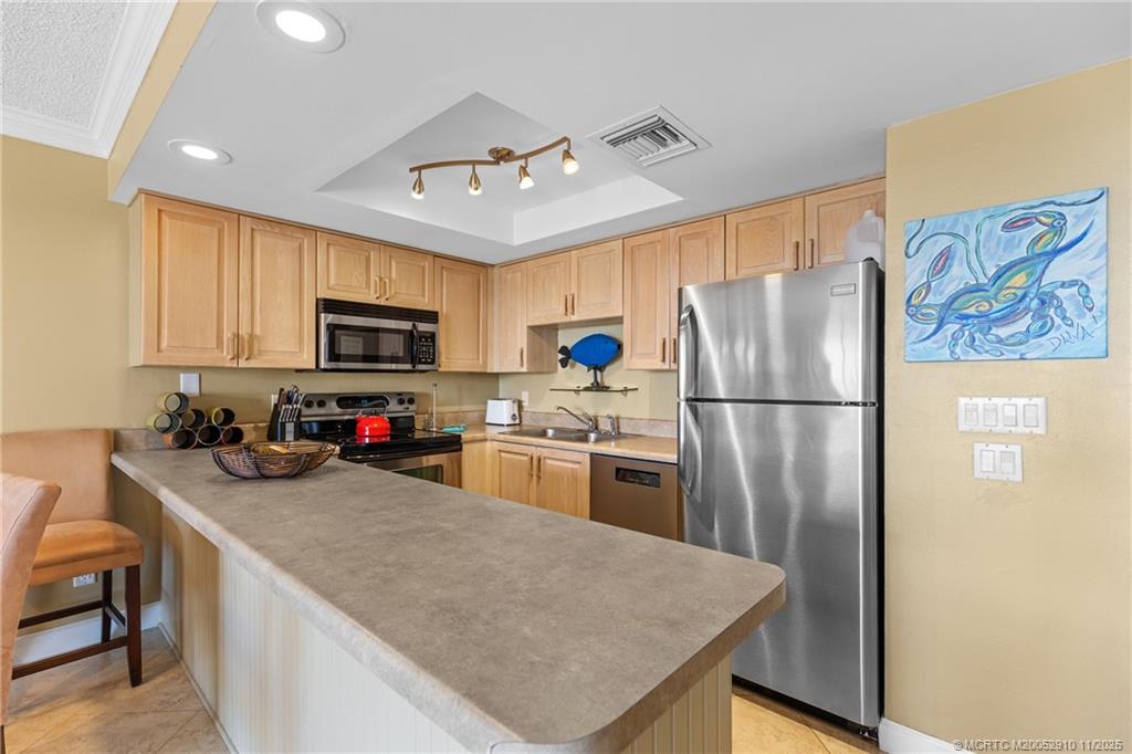 379 Northeast Tradewind Lane, Unit 1104 Stuart, FL 34996 - Photo 18 of 30 a kitchen with a refrigerator a stove a microwave a sink and cabinets