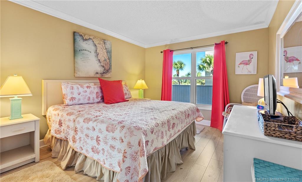379 Northeast Tradewind Lane, Unit 1104 Stuart, FL 34996 - Photo 19 of 30 a bedroom with a bed a dresser and painting on the wall
