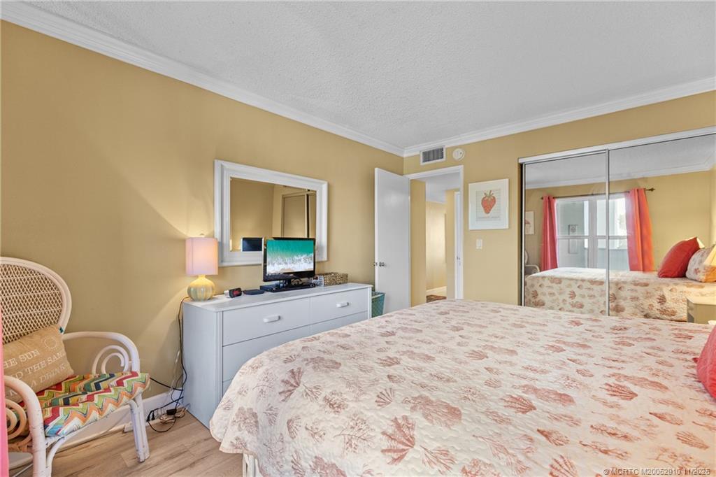 379 Northeast Tradewind Lane, Unit 1104 Stuart, FL 34996 - Photo 22 of 30 a bedroom with a bed and wooden floor