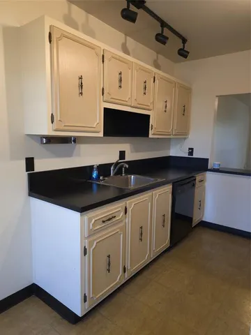 a kitchen with stainless steel appliances granite countertop white cabinets sink and window