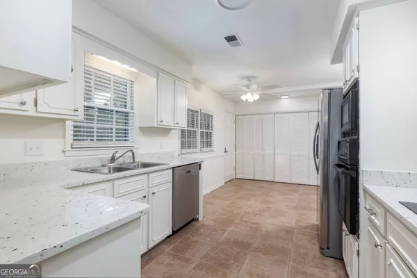 a kitchen with granite countertop a sink cabinets stainless steel appliances and a window