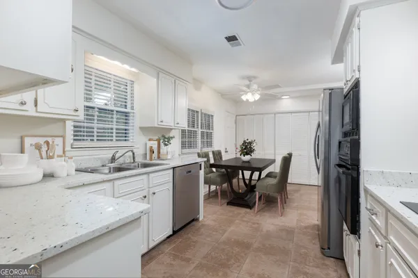a kitchen with kitchen island a dining table chairs sink and cabinets