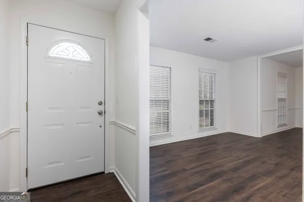 an empty room with wooden floor closet and windows