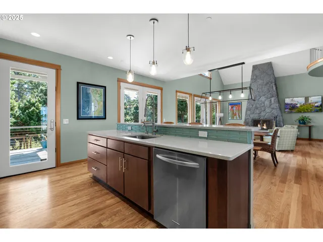 a open kitchen with stainless steel appliances granite countertop a sink dishwasher a stove and a dining table with wooden floor