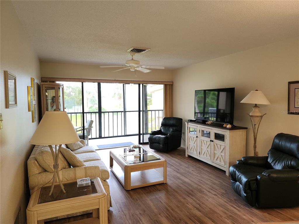 4260 Placida Road, Unit 21D Englewood, FL 34224 - Photo 11 of 38 a living room with furniture floor to ceiling window and a flat screen tv