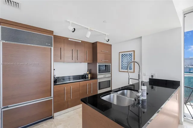 a kitchen with granite countertop a sink and a refrigerator