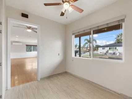 a view of an empty room with window and wooden floor