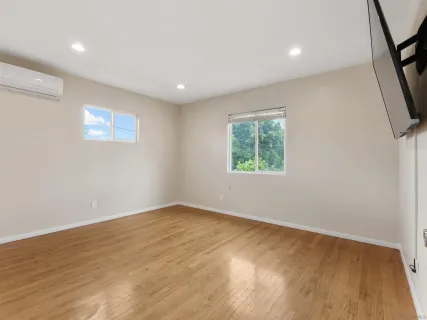 an empty room with wooden floor and windows