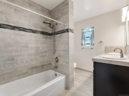 a bathroom with a granite countertop sink a mirror a bathtub and shower