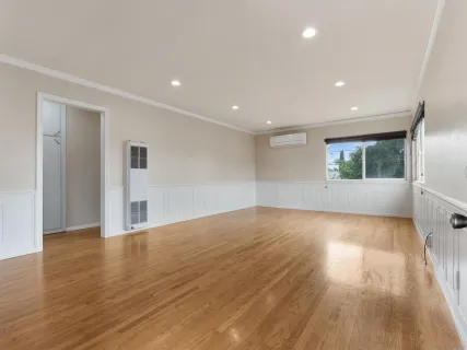 a view of a big room with wooden floor and windows