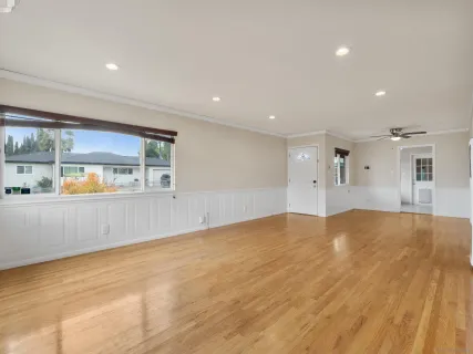 a view of an empty room with window and wooden floor