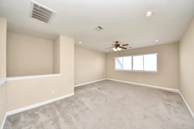 an empty room with windows and ceiling fan