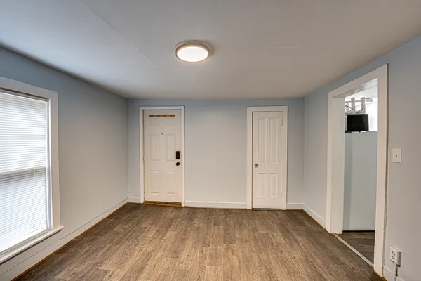 an empty room with wooden floor and windows