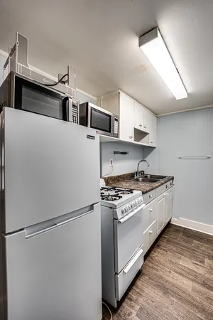 a kitchen with stainless steel appliances white cabinets and wooden floor