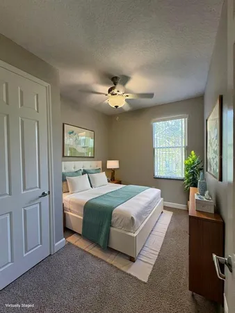 a bedroom with a large bed and a chandelier fan