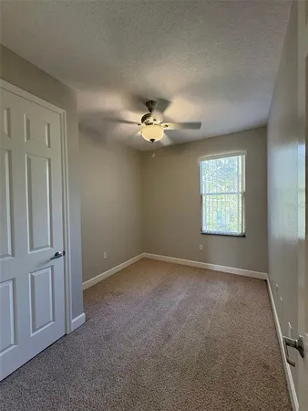 an empty room with windows and fan