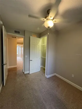 an empty room with chandelier fan and windows
