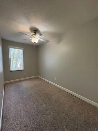 an empty room with a chandelier fan and windows