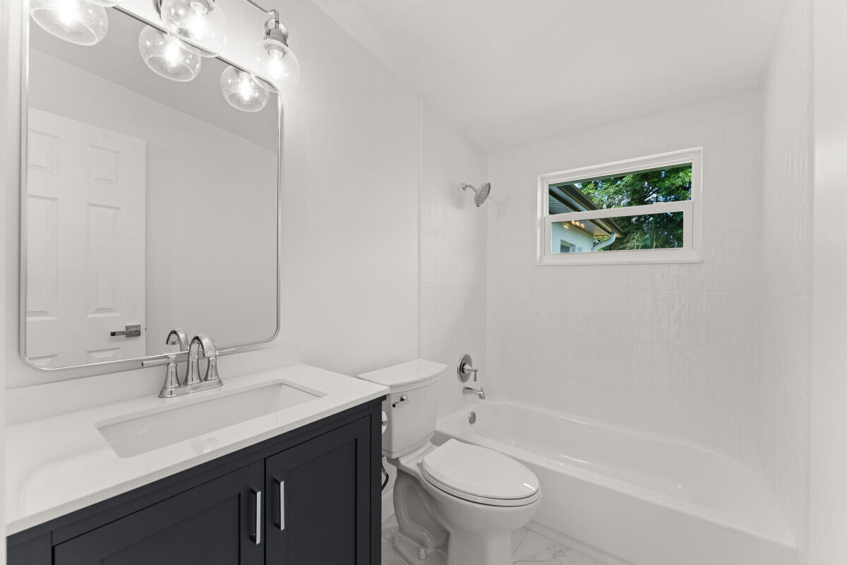 3797 Bahama Road Palm Beach Gardens, FL 33410 - Photo 14 of 33 a bathroom with a sink a toilet a mirror a vanity and bathtub
