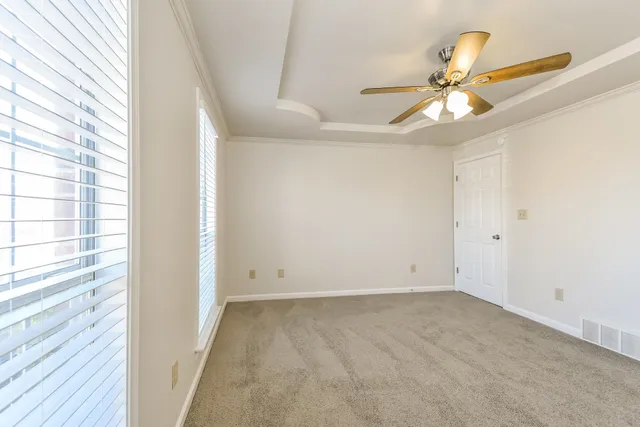 an empty room with windows and fan