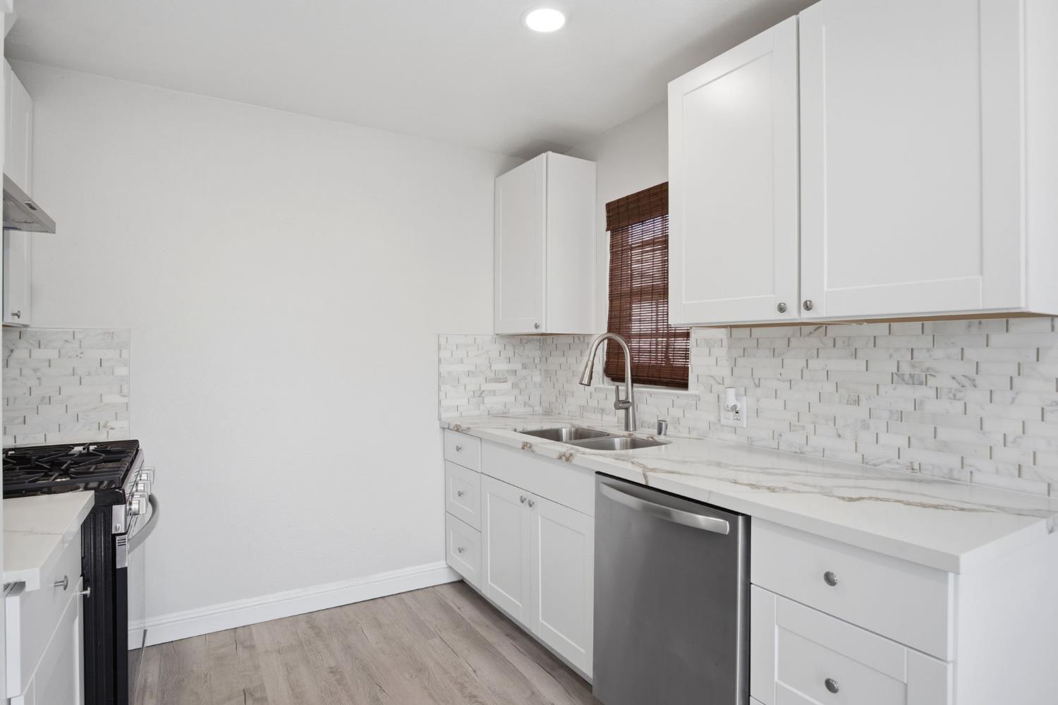 341 2nd Street Livingston, CA 95334 - Photo 10 of 19 a kitchen with a sink dishwasher and white cabinets with wooden floor